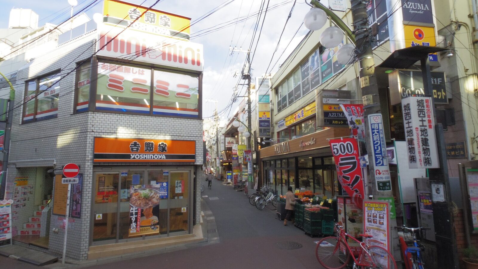東京明大前站附近的商店街，街口有牛丼店與便利商店